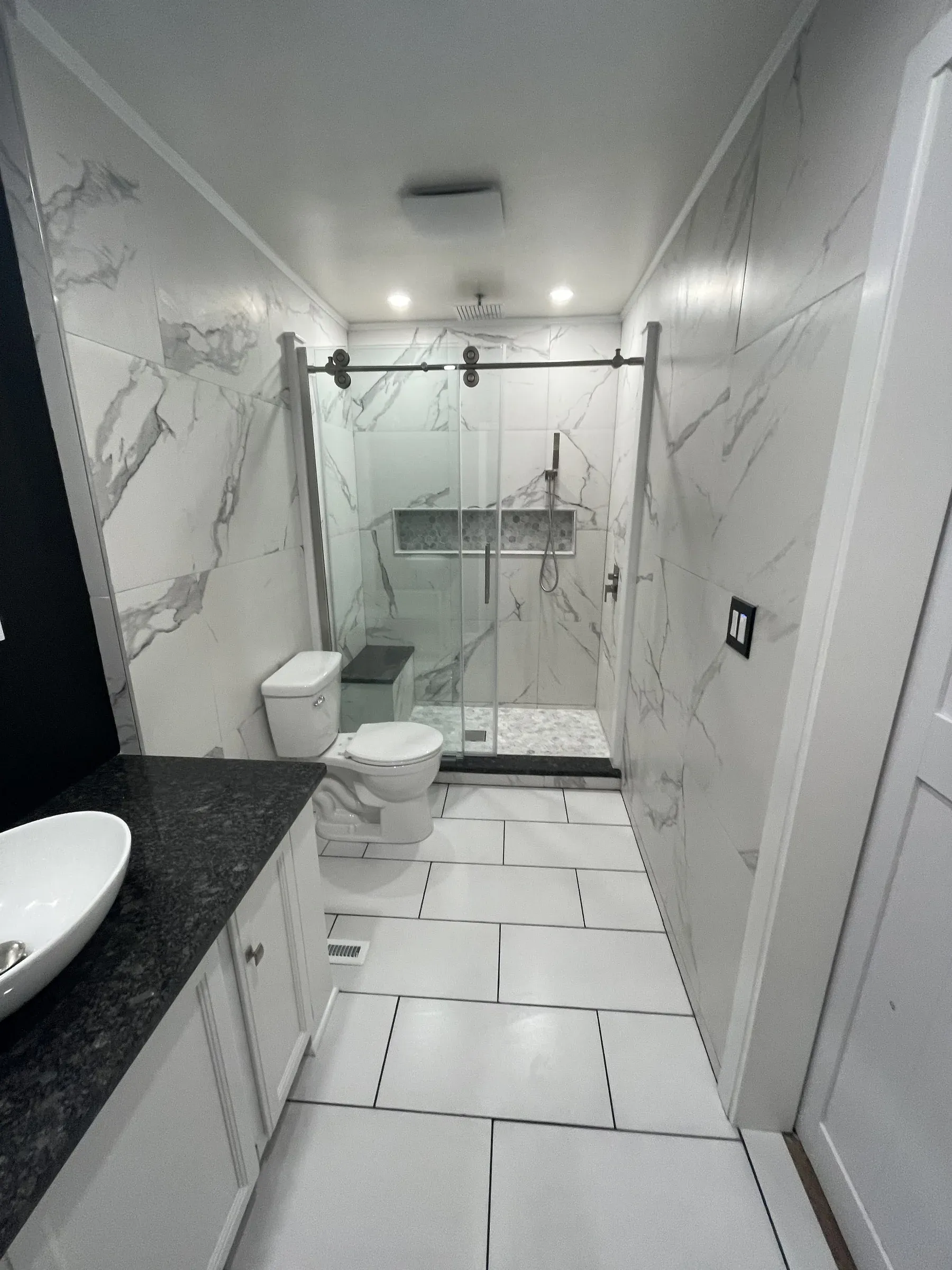 Full bathroom remodel in Wilmington DE with floor-to-ceiling Calacatta marble walls, frameless sliding glass shower and floating vessel sink vanity by Zavala & Sons